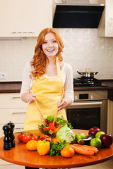 Smiling young happy housewife mixing fresh salad