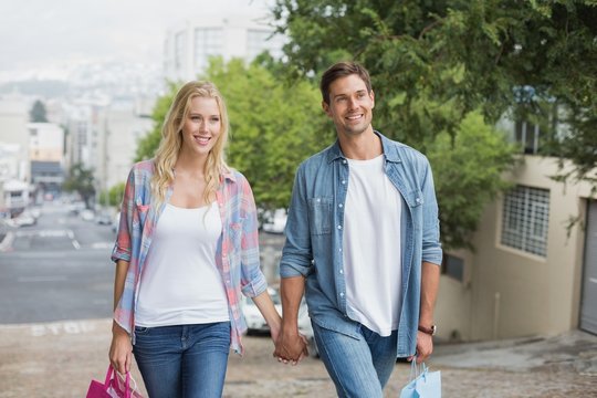 Hip young couple on shopping trip walking uphill