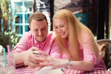 Cheerful couple surfing the web, looking a photo on smartphone,