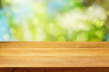 Empty wooden deck table over garden bokeh background