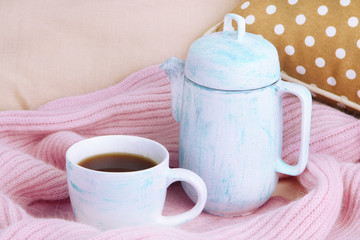 Cup and teapot with scarf on bed close up