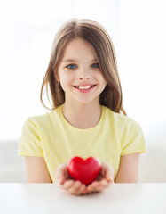 smiling little girl with red heart at home