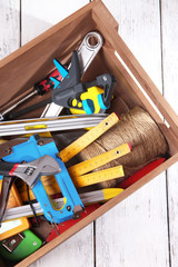 Wooden box with different tools, on wooden background