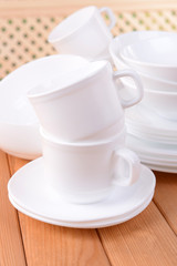 Fototapeta na wymiar Set of white dishes on table on light background