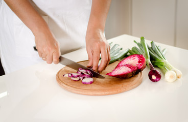 Obraz na płótnie Canvas Housewife chopping vegetables in the kitchen