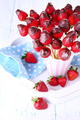 Strawberry in chocolate on skewers in cup on table close-up
