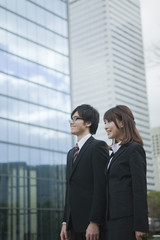 ビルの前で立つビジネスウーマンとビジネスマン