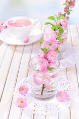 Beautiful fruit blossom in glass on table on light background