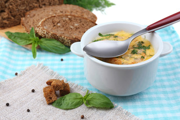 Tasty soup in saucepan on tablecloth, close up