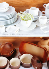 Different tableware on shelf, on wooden background
