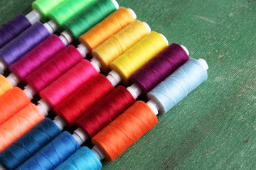 Multicolor sewing threads on wooden background