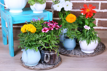 Flowers in  decorative pots on chair, on bricks background