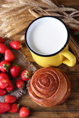 Fototapeta premium Ripe sweet strawberries, fresh bun and mug with milk