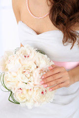 Bride holding wedding bouquet of white peonies, close-up,