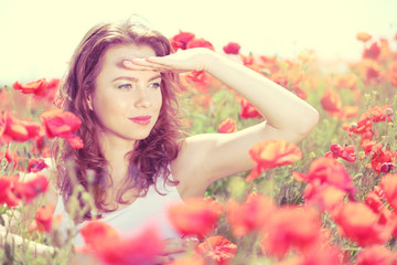 Obraz na płótnie Canvas Beautiful young woman in poppy field