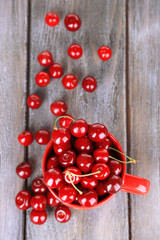 Sweet cherries in mug on wooden background