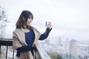 展望台から神戸の景色の写真を撮る笑顔の女性