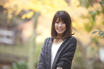 秋の紅葉した公園で立っている笑顔の女性