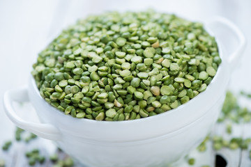 Glass bowl with split dried green peas, close-up, studio shot