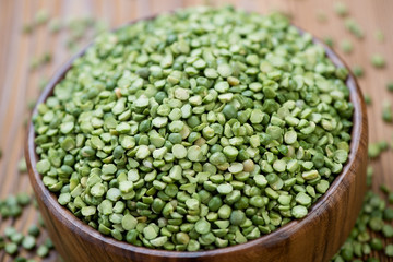 Close-up of split dried green peas in a wooden bowl, studio shot