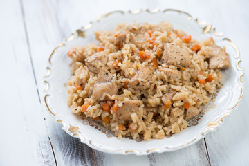 Glass plate with chicken pilaf over white wooden background