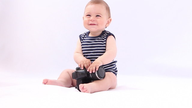 Baby boy playing with photocamera against white background