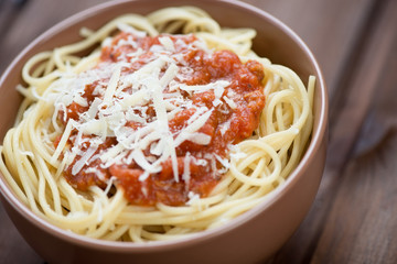 Glass bowl with spaghetti bolognese over wooden background