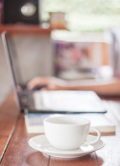 Obraz na płótnie Canvas Woman using laptop with a white cup of coffee