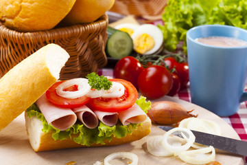 Breakfast sandwich with vegetables and a cup of hot cocoa.