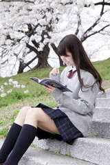 桜の木の下で勉強する女子高生