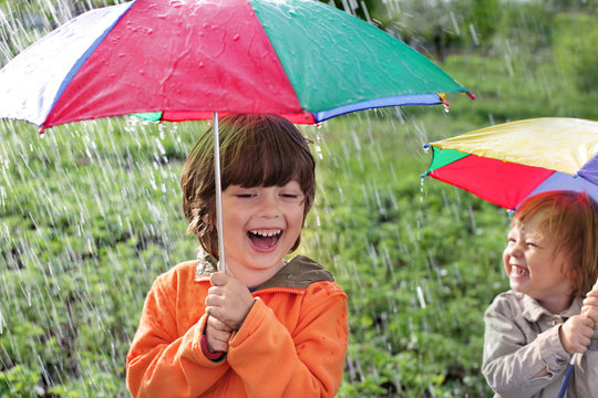two happy brother with umbrella outdoors