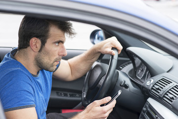 Man driving car and holding phone, dangerous concept.