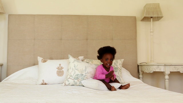 Cute baby girl standing and clapping on bed