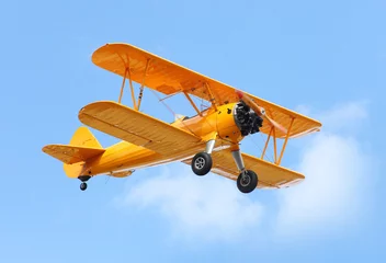 Foto auf Acrylglas Alte Flugzeuge Gelber Doppeldecker am blauen Himmel.