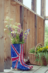 Fototapeta na wymiar Wild flowers in Union Jack rubber boots-wellies on a country hou