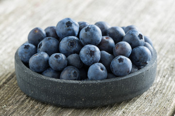 bowl of fresh blueberries on a wooden background