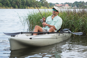 Man Fishing in Kayak in grassy waters - 66346934