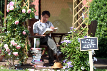 Schild "Lesezeit" lesender Mann im Hintergrund