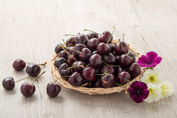 Cestino in vimini con ciliegie e fiori freschi
