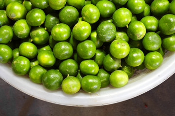 close up many green lemon in plastic basket