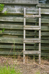 Weathered wooden ladder leaning on wooden slats