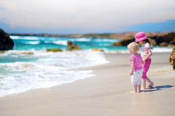 Two little sisters having fun on a beach