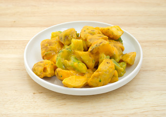 Broccoli and potatoes in cheese sauce TV dinner on table