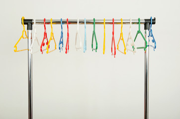 Rack of clothes with colorful empty plastic hangers on display.