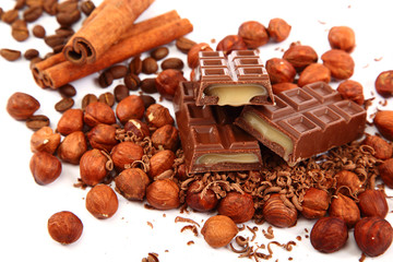 Stack of chocolate tiles with hazelnuts and cinnamon sticks.