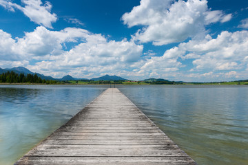 wooden boardwalk at swim lake hopfen with blue sky in spring