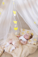 Cute girl in cream crib and canopy