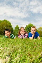 drei kinder liegen im gras