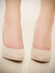 Closeup of female feet in beige high heels.