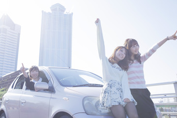 遠くを指差す女性と、車の前で楽しそうに手を上げる友達